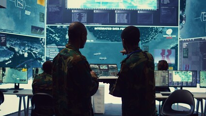 Intelligence analysts supervising and coordinating the big data analysis, processing tactical information to help the field troops. Officers monitoring real time warfare information. Camera B.