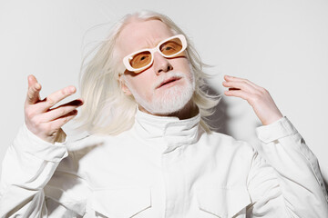 Stylish man with long white hair and beard wearing trendy white outfit and sunglasses on a clean, minimalistic white background, showcasing modern fashion aesthetics and confidence