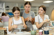 © JackF - Young woman teacher explains to girl students how to sculpt ceramics in workshop..