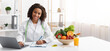 © Prostock-studio - Cheerful afro woman dietologist working with laptop in modern office, having fresh juice, fruits and vegetables on table