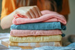 © Phichitpon - Feel softness, chore of asian young woman, girl hand holding pile clothing from table, stack folding clean clothes after washing, laundry and dry. Household working at home. Laundry of maid concept.