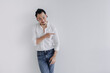 © Sevendeman - Smile long hair Asian man bun in white shirt and jean pointing at empty space.