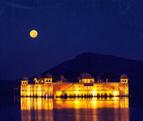 Vintage retro hipster style travel image of Rajasthan landmark - Jal Mahal (Water Palace) on Man Sagar Lake at night in twilight with grunge texture overlaid. Jaipur, Rajasthan, India