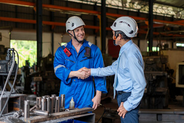 young caucasian technician ้hand shaking with old experience manager who examining lathe machine,workers working in small welding industry