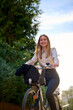 © Cavan Images - Business young woman biking through a sunlit urban area