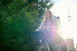 © Cavan Images - Business young woman biking through a sunlit urban area