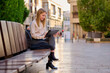 © Cavan Images - Woman working on a tablet while sitting on a bench in a city street