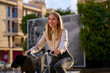 © Cavan Images - Young woman cycling joyfully on a paved path in an urban city