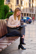 © Cavan Images - Woman working on a tablet while sitting on a bench in a city street