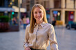 © Cavan Images - Young woman smiling confidently on a sunny day in an urban city square