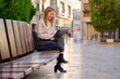 © Cavan Images - Woman working on a tablet while sitting on a bench in a city street