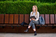 © Cavan Images - Young woman sitting on a bench in a park while holding a tablet