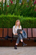 © Cavan Images - Young woman sitting on a bench in a park while holding a tablet