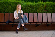 © Cavan Images - Young woman sitting on a bench in a park while holding a tablet