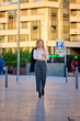 © Cavan Images - Young woman in business attire checks her phone in a city setting