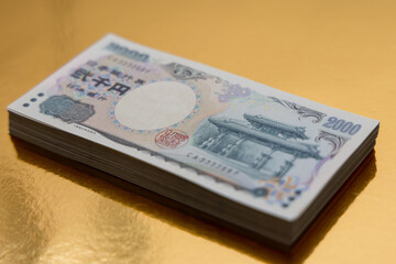 Stack of 2000 yen bills neatly placed on a golden surface highlighting the intricate design of the currency and symbolizing financial prosperity and wealth