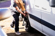 © Johnér - Female mechanic using socket wrench to fasten nut of mini van tire at sunny day