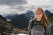 © Johnér - Portrait of smiling mid adult woman on mountain against cloudy sky