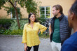 © Johnér - Smiling woman with hand on hip talking with male neighbors outside building