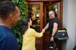 © Johnér - Mature woman greeting repairman with handshake while standing near door of building