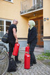 © Johnér - Happy male and female repairperson carrying fire extinguisher while standing near residential building on footpath