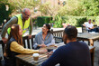 © Johnér - Happy male and female architects discussing with couple sitting on bench in garden