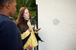 © Johnér - Female building inspector holding smart phone examining wall of building while standing with male resident