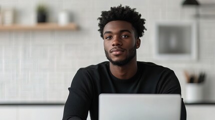 Black man sitting in white office with laptop blurred copy space