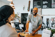 © Johnér - Smiling cafe worker giving serving dish to coworker