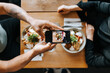 © Johnér - Midsection of couple photographing food with mobile in restaurant