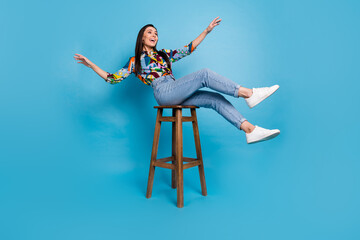 Wall Mural - Full length photo of careless funny woman wear print shirt jeans falling from stool look empty space isolated on blue color background