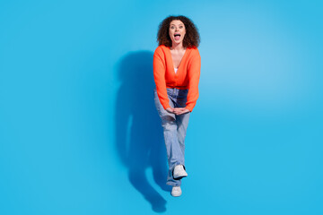 Wall Mural - Photo of wavy haired model woman wearing orange cardigan and jeans boogie woogie move at discotheque isolated on blue color background