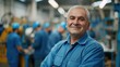 © Veronika - Portrait of smiling middle aged male worker in blue uniform standing with group workers working at factory
