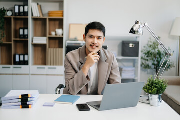 Young handsome man typing on tablet and laptop while sitting at the working table