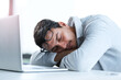 © peopleimages.com - Tired businessman, sleeping and rest with laptop on desk for lazy day, done or finished at office. Young, man or employee asleep on table with computer for fatigue, burnout or dreaming at workplace