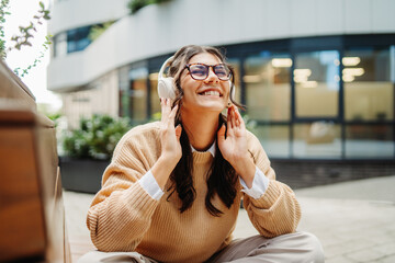 Young caucasian woman listening to music or audiobook outdoors