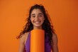 © Vii - A woman holds a large orange yoga mat, ready for practice