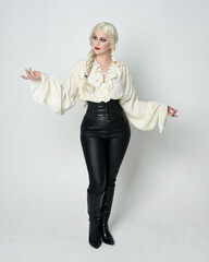 Poster -  Full length portrait of pretty  female model wearing vintage gothic fantasy blouse, black leather pants, blonde plaited hair.  Standing pose, walking  forwards, isolated on white studio background.