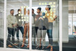 © peopleimages.com - Business people, brainstorming and schedule planning with glass board for meeting or collaboration at office. Young, group or employees writing with teamwork for agenda, tasks or reminder for project