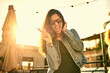 © peopleimages.com - Portrait, peace sign and happy woman with sunglasses in city at sunset outdoor. Face, excited and girl with v hand gesture on rooftop for cool fashion, funny emoji and laughing on holiday in Brazil