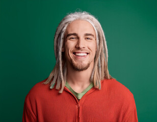 Studio Portrait of Handsome Young Man Happily Smiling Against Green Background