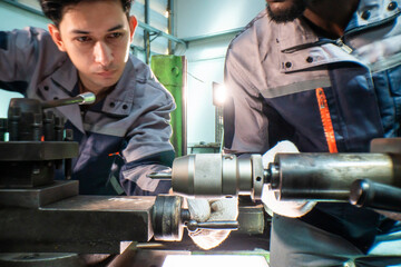 two focused industrial technicians work together operating heavy machinery in a workshop. the image 