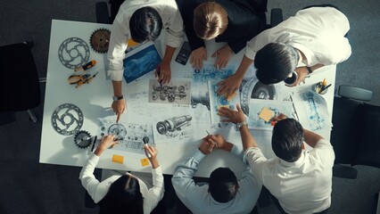 Top down aerial view of smart engineer team working together to design turbine engine. Professional technician discussing about jet engine construction while pointing at part of engine. Alimentation.