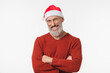 © InsideCreativeHouse - Happy mature middle-aged man wearing Christmas Santa Claus red hat with arms crossed looking at camera isolated in white background. New Year Merry Christmas winter holidays concept