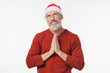 © InsideCreativeHouse - Caucasian mature middle-aged man praying to God meditating asking for presents wearing Santa Claus red hat isolated in white background. New Year Merry Christmas winter holidays concept