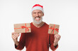 © InsideCreativeHouse - Extremely happy cheerful caucasian mature middle-aged man in red Santa Claus hat celebrating Christmas, feeling positive emotions because of presents gifts isolated in white background