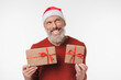© InsideCreativeHouse - Pensive thoughtful caucasian mature middle-aged man in red Santa Claus hat holding Christmas New Year presents thinking isolated in white background. Sale offer discount