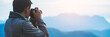 © arrowsmith2 - The photographer with jacket taking photo by a camera in a mountains. Creative professional photographing.Travel, hobby and active lifestyle concept