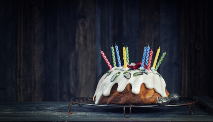 delicious birthday cake with colorful candles on wooden background