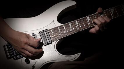 Guitarist Playing Guitar In Studio. Low key of man hand play white electric guitar for songs and cover music or skill practice. Close up of musician playing guitars instrument against black background